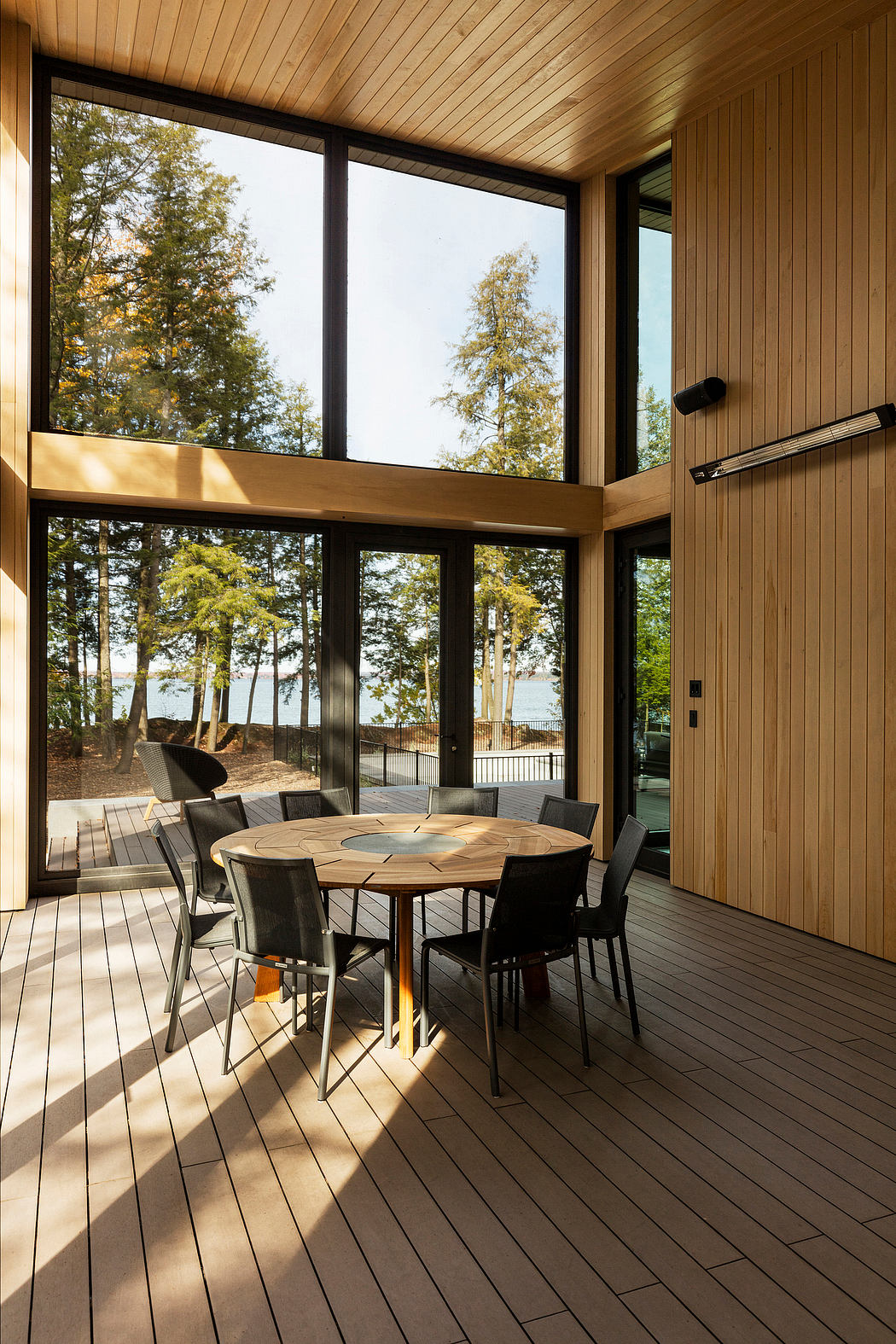 Spacious wooden cabin interior with large windows overlooking a forested landscape.