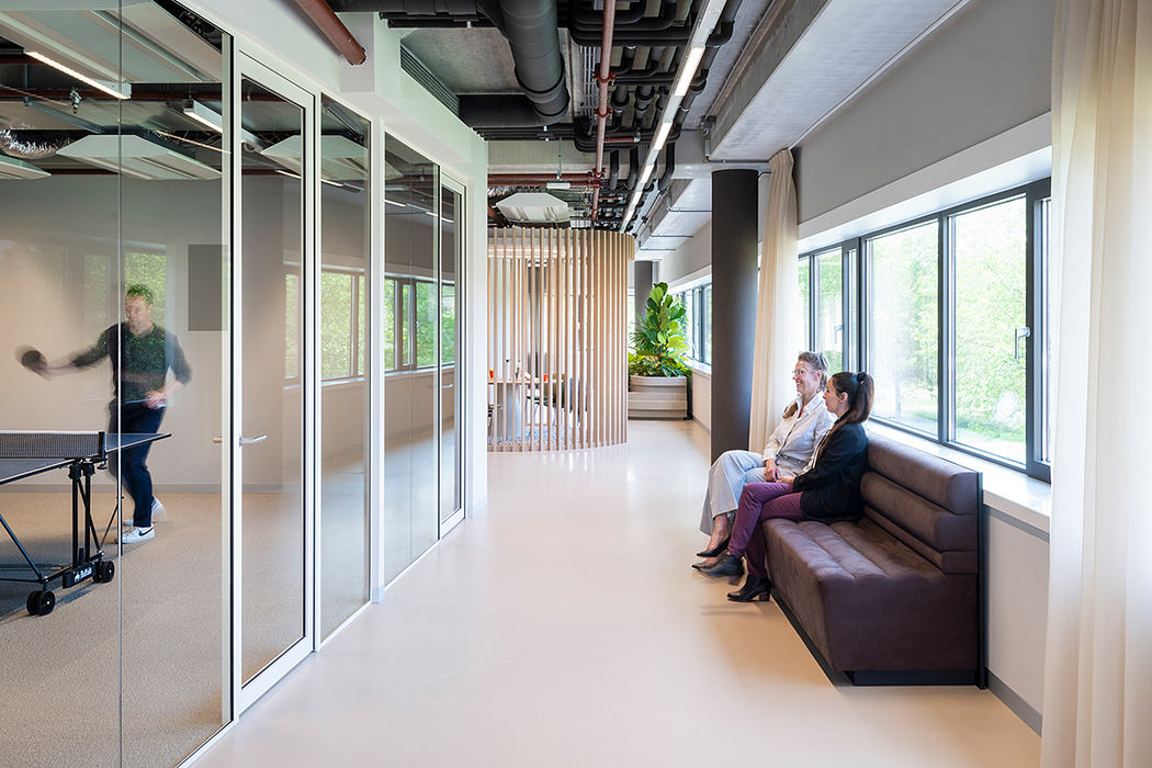 Sleek, modern office interior with glass walls, wood accents, and comfortable lounge seating.