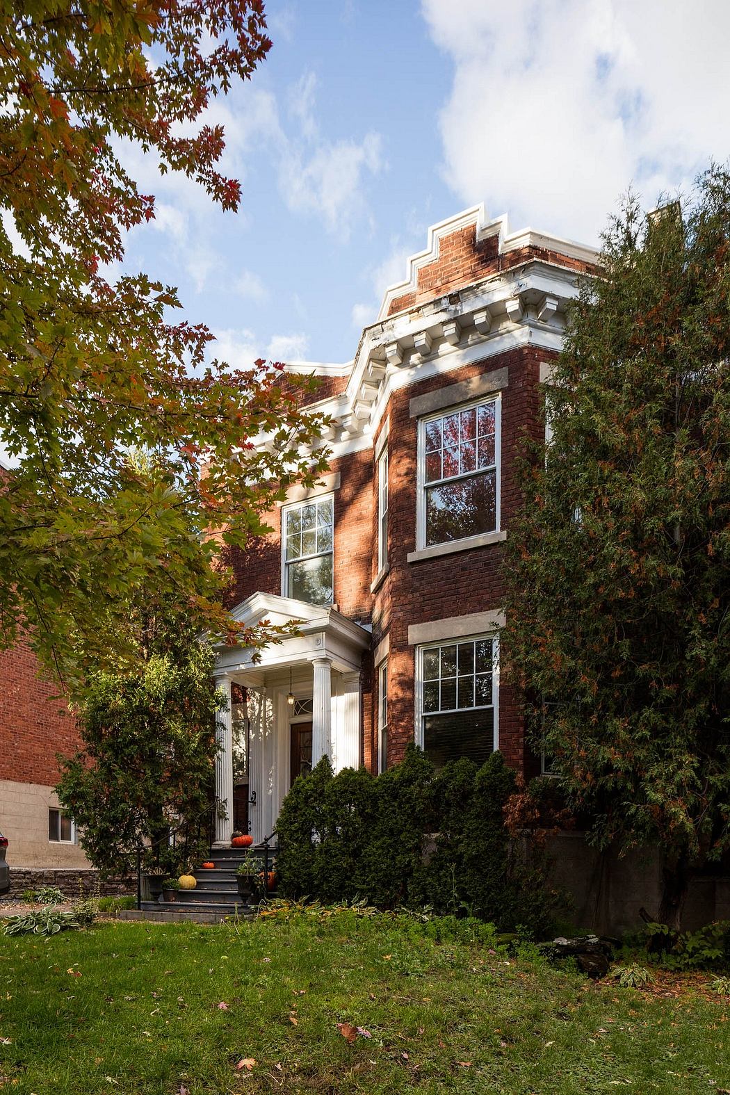 Stately brick building with ornate facade, nestled amongst autumn foliage.