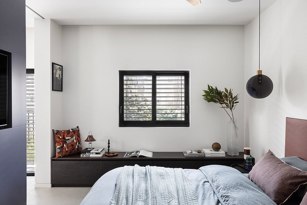 Minimalist bedroom with dark furniture, framed artwork, and a distinctive lighting fixture.