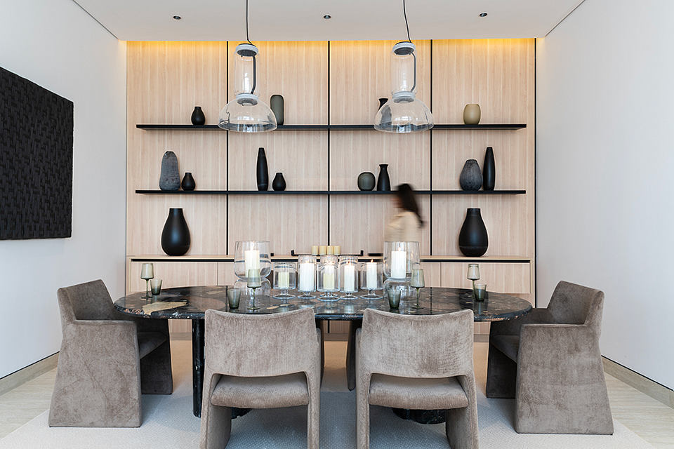 Sleek, modern dining area with black shelves displaying decorative vases and pendant lights.