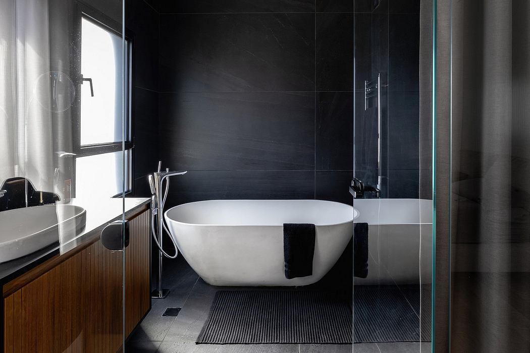 A modern bathroom with a freestanding bathtub, sleek black tiles, and a minimalist design.