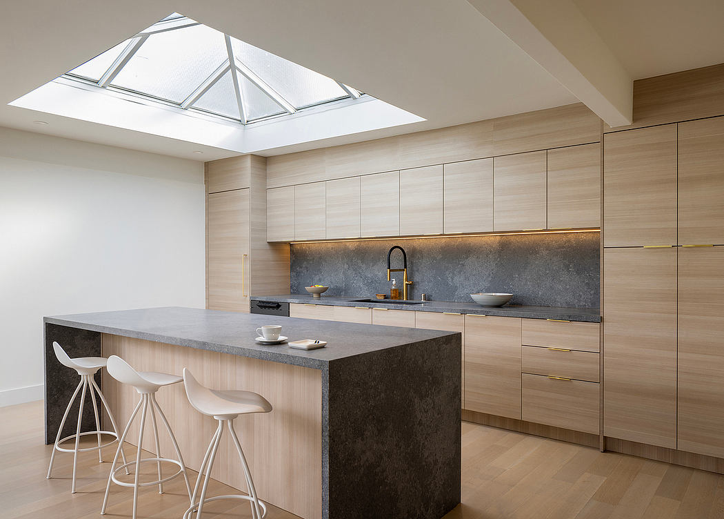 Sleek modern kitchen with large skylight, wood cabinetry, and stone countertops.