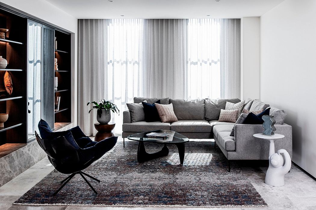 Contemporary living room with gray sectional sofa, black armchair, and ornate area rug.