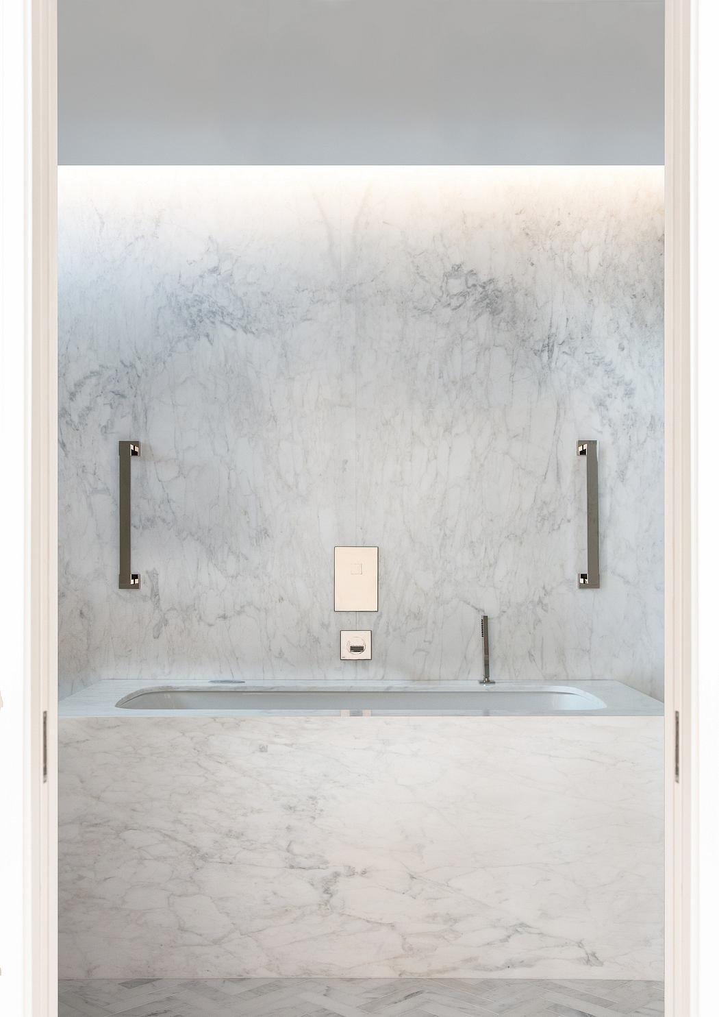 Sleek and modern bathroom design with marble walls, built-in tub, and minimalist fixtures.