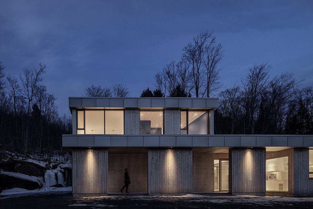 Modern two-story home with large windows, wooden siding, and exterior lighting.
