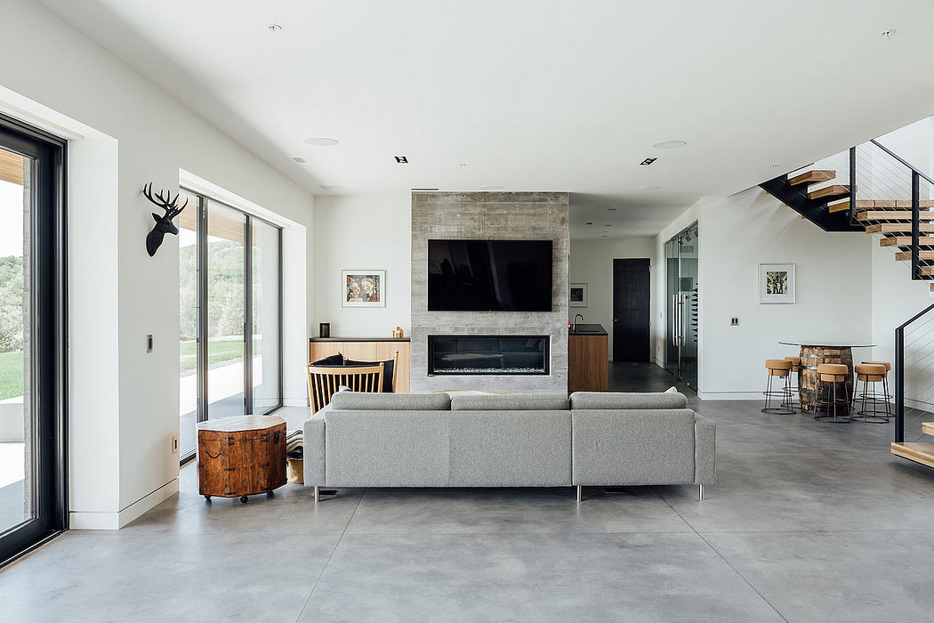 Spacious modern living room with minimalist decor, concrete floors, and a fireplace.