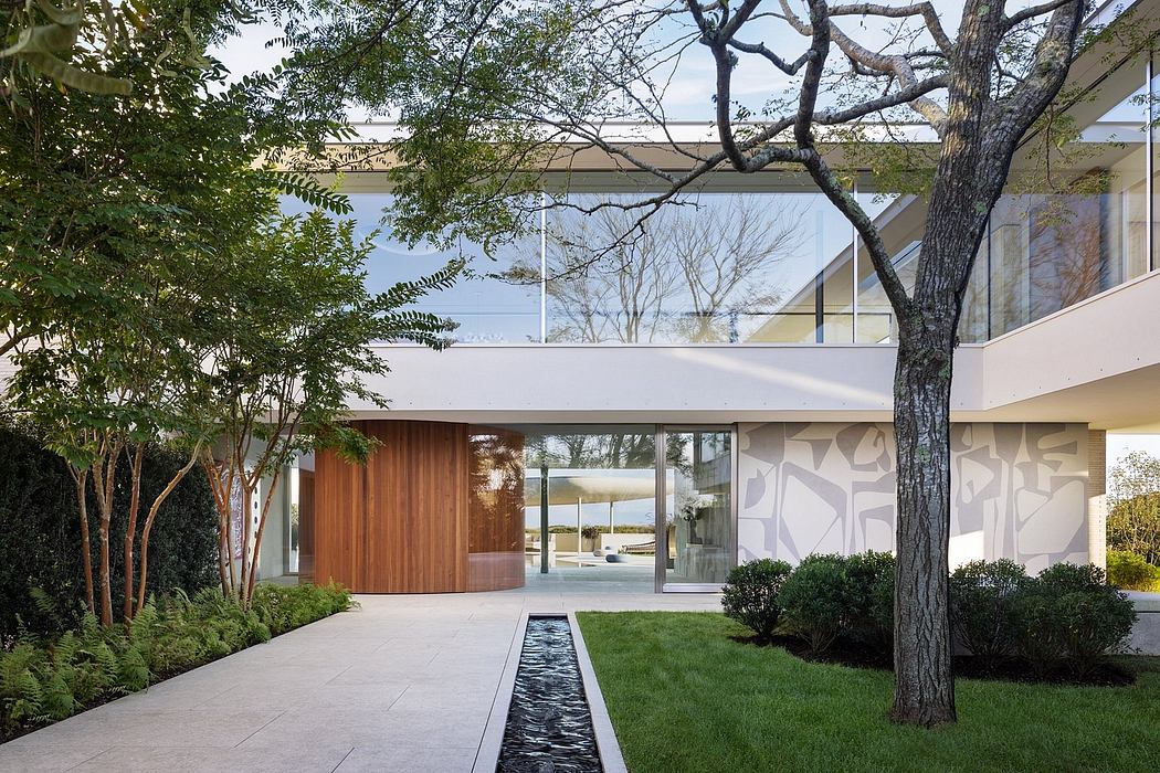 Modernist glass and wood home with a tranquil water feature and lush landscaping.