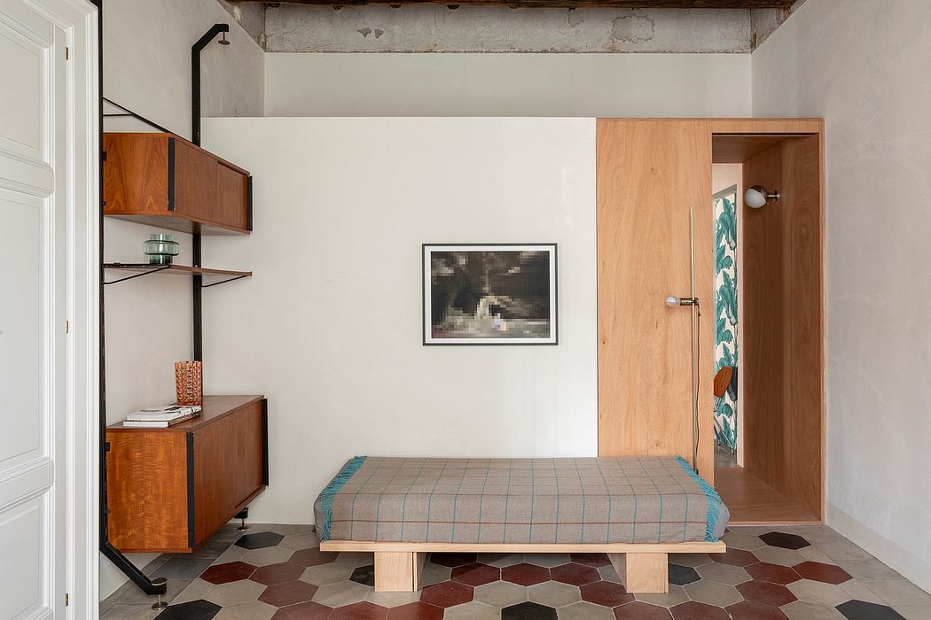 Minimalist, modern bedroom with wooden shelving, tiled hexagonal flooring, and a framed artwork.