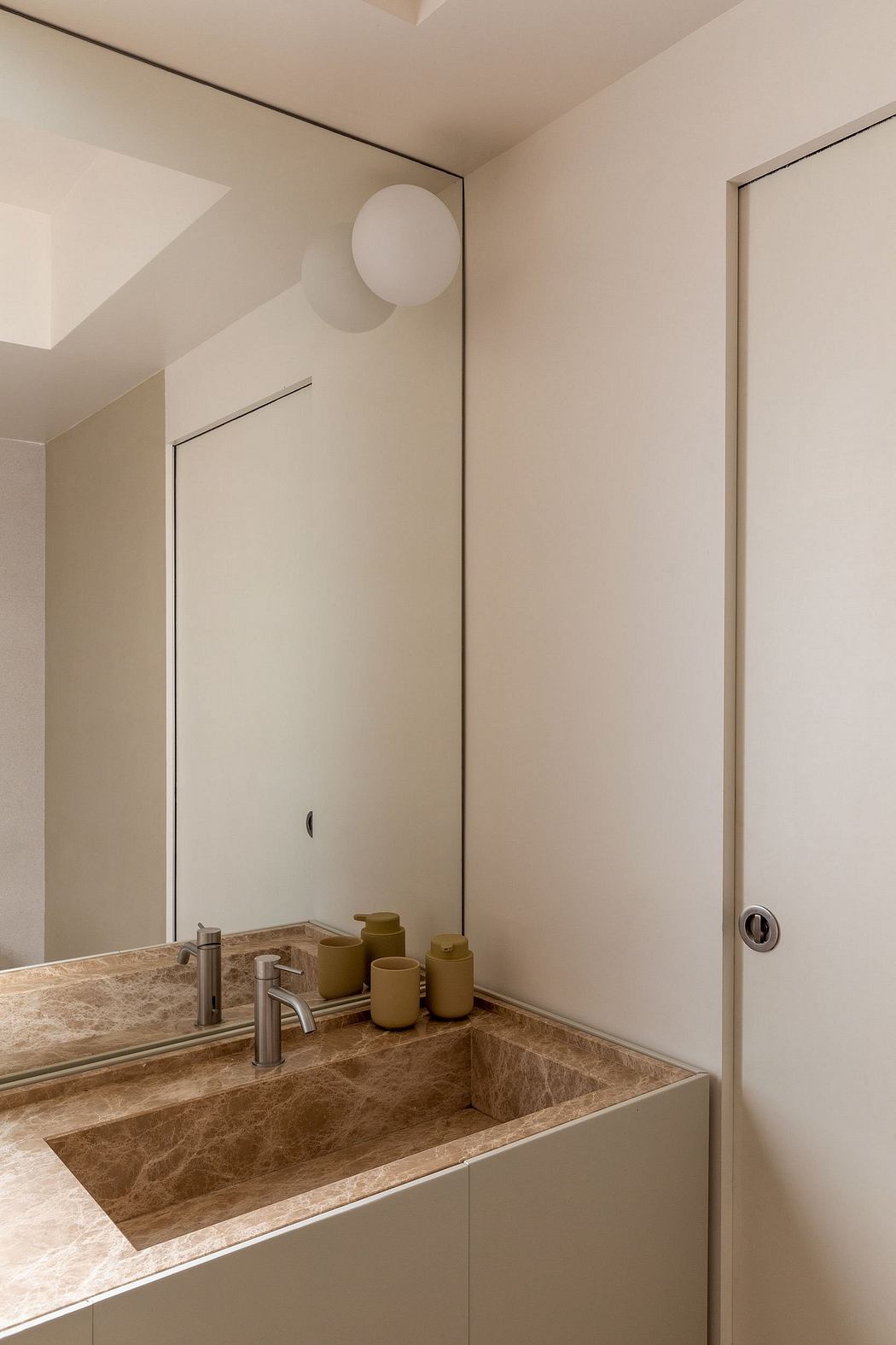 Minimalist vanity with a natural stone sink and recessed lighting in a neutral-toned bathroom.