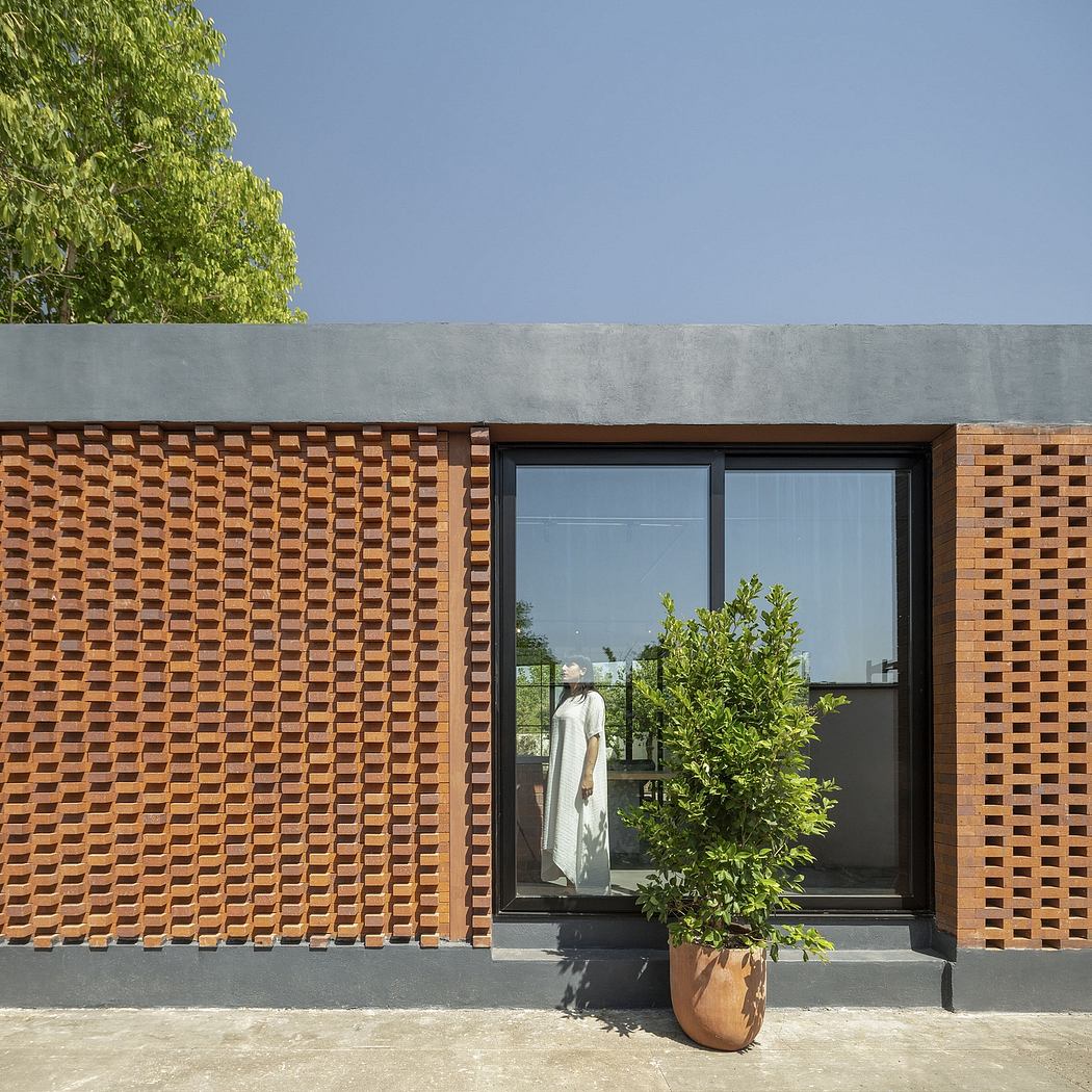 Striking brick façade with large glass windows, contrasting with potted plant.