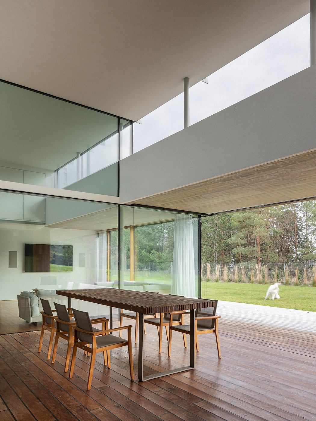 Spacious modern interior with wooden flooring, glass walls, and outdoor view.