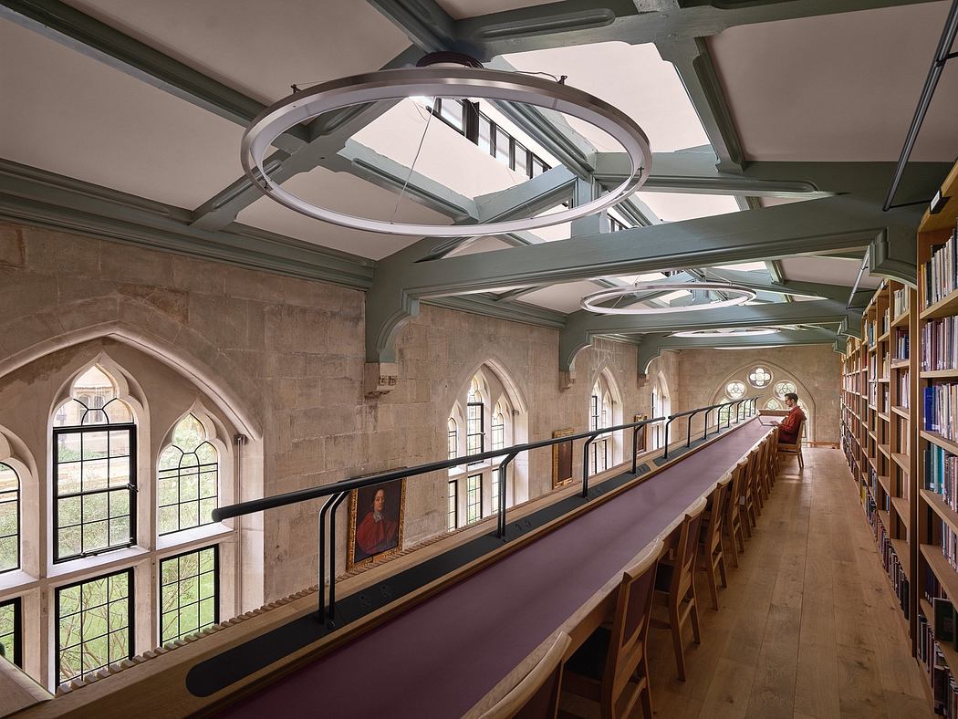 A grand library interior with arched windows, suspended lighting, and ornate balcony.