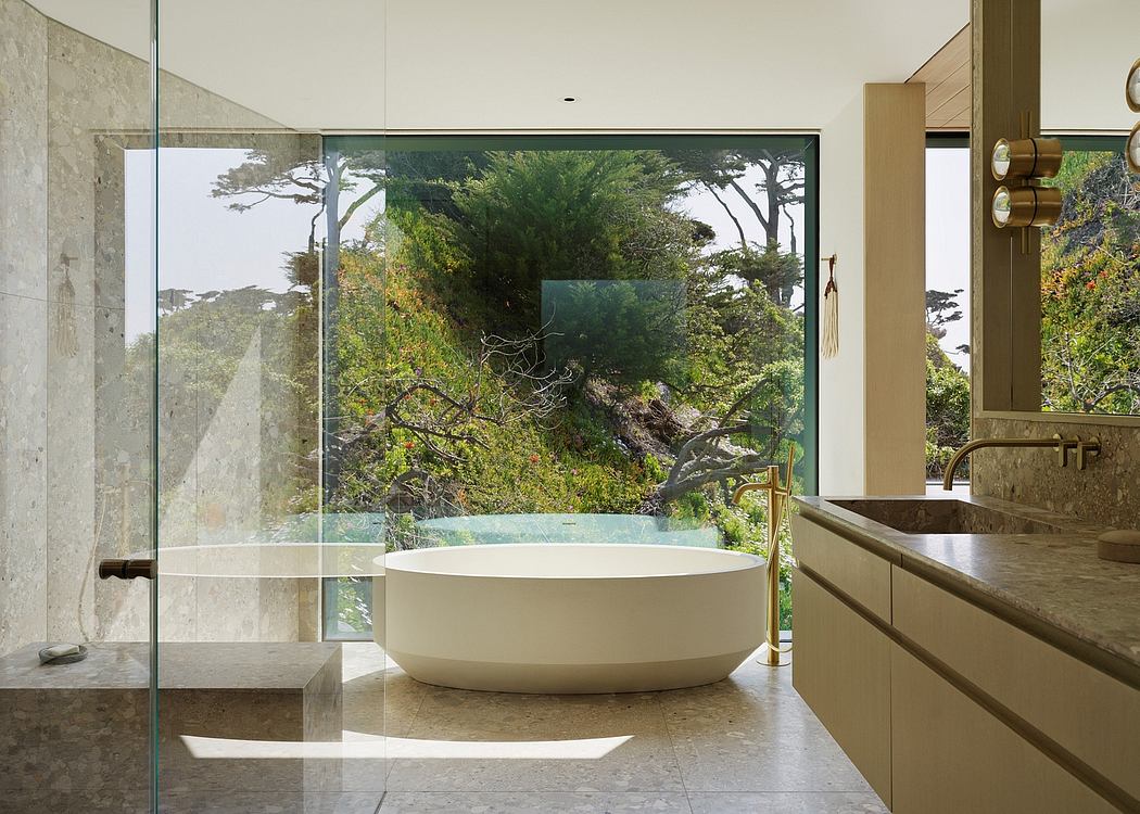 Luxurious bathroom with a freestanding oval tub and panoramic forest views through glass walls.