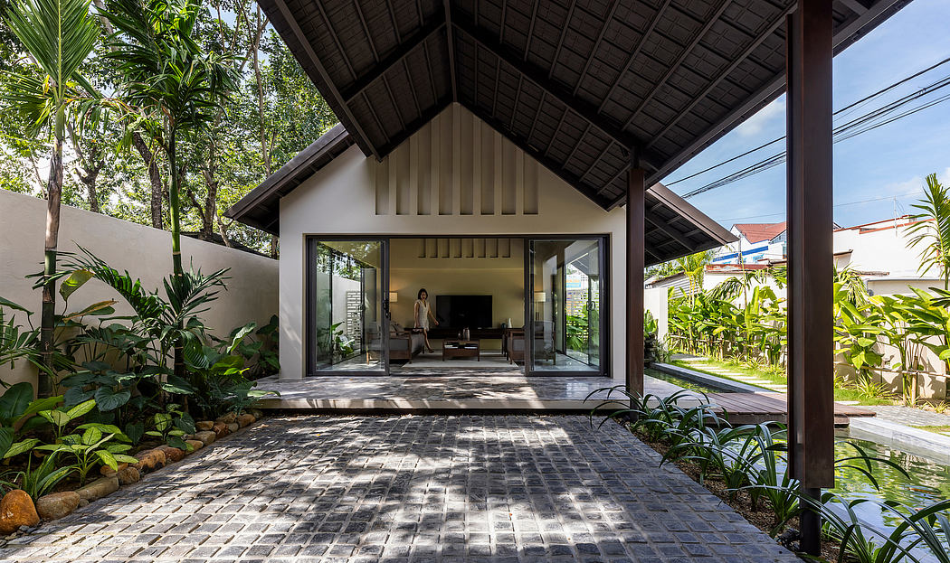 Tropical open-plan home with exposed wooden beams, sliding glass doors, and lush garden.