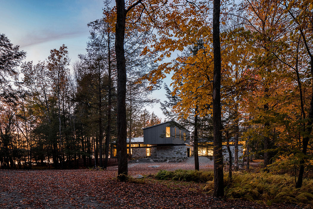 Modern stone and glass home nestled among vibrant autumnal foliage.