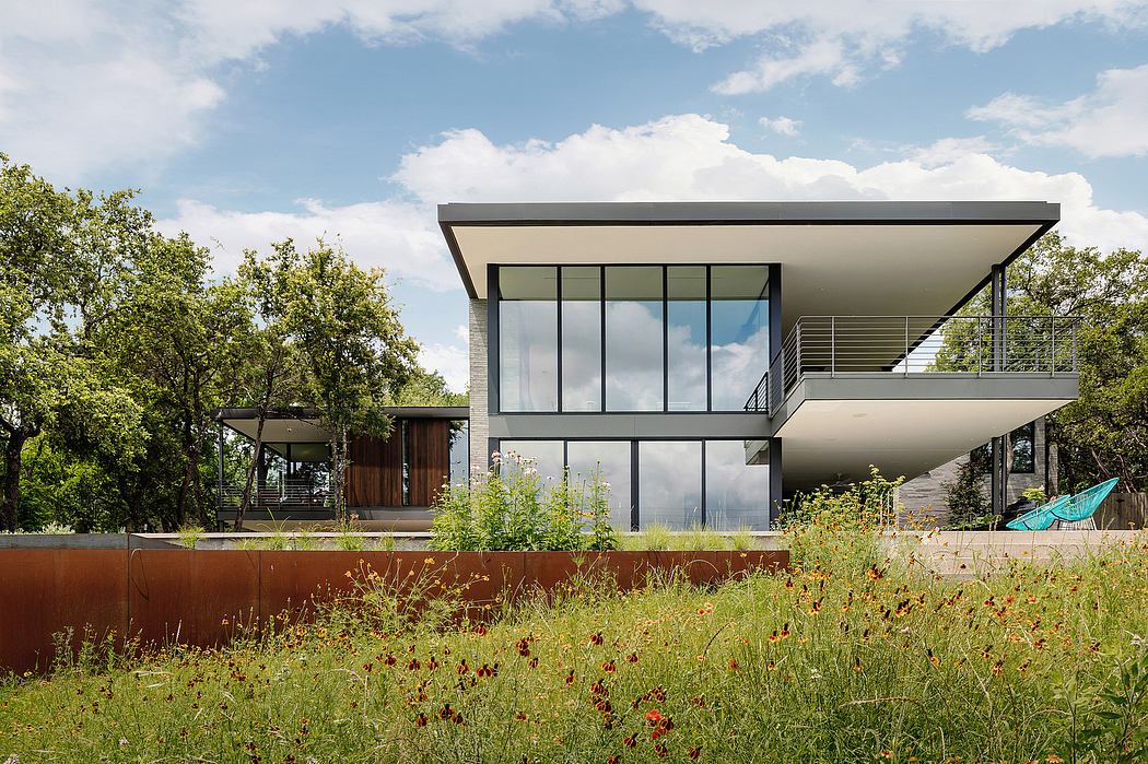 Modern two-story home with floor-to-ceiling windows, concrete walls, and lush garden.