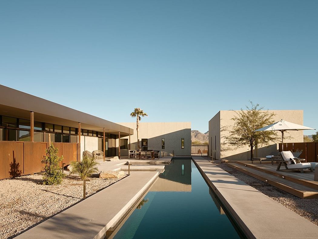 Modern desert home with sleek architecture, pool, and lounge area in foreground.