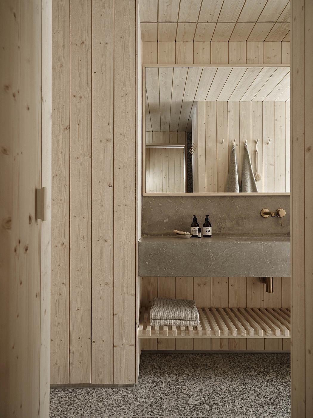 Minimalist wood-paneled bathroom with concrete vanity and built-in shelving.