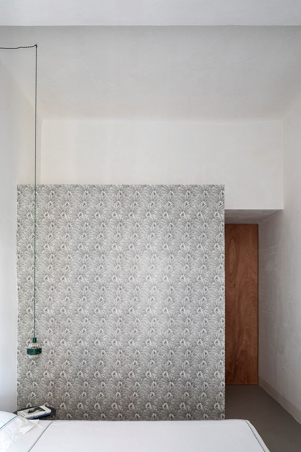 Modern bedroom with a bold, patterned feature wall and a wooden door frame.
