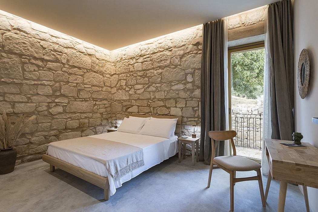 Rustic stone bedroom with wooden furnishings, large window, and minimalist decor.