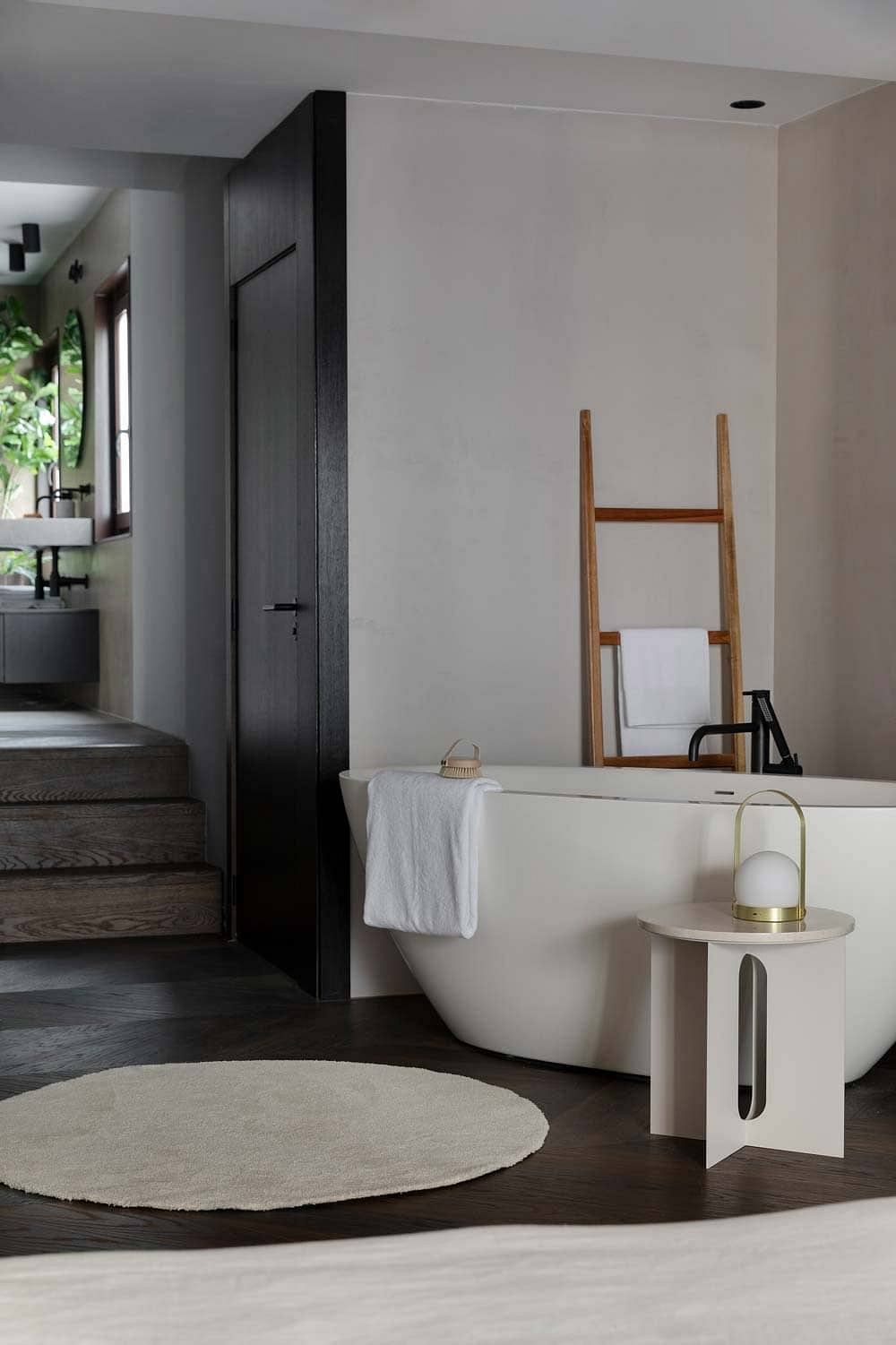 Minimalist bathroom with a freestanding tub, wooden ladder, and contemporary decor.