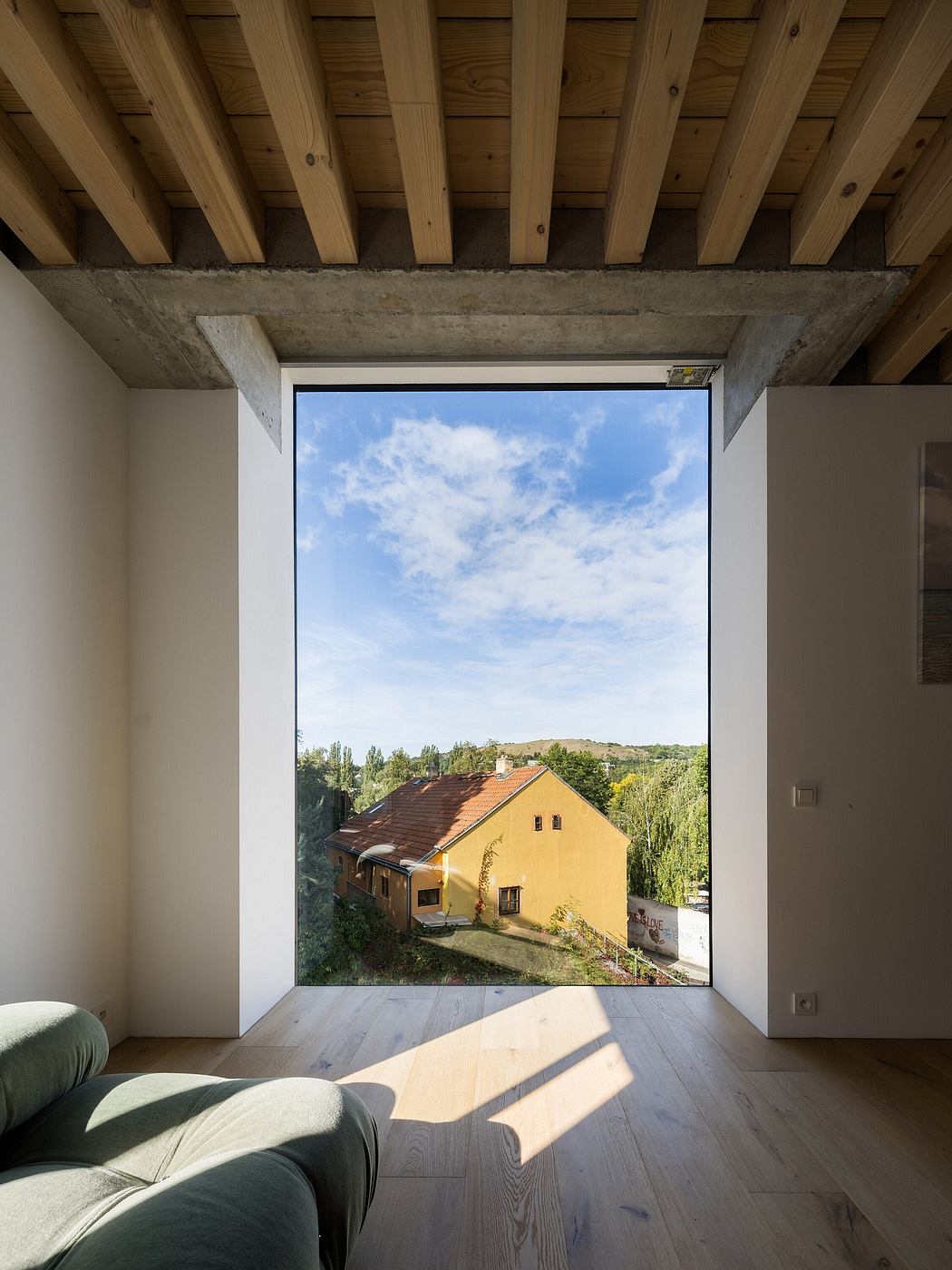 Spacious room with exposed wooden beams, concrete frame, and expansive window framing rural landscape.