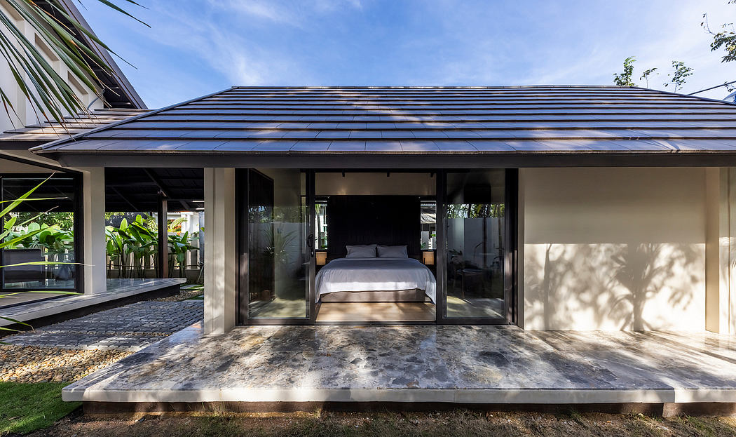 Modern tropical home with sleek glass walls, slate roof, and lush outdoor surroundings.