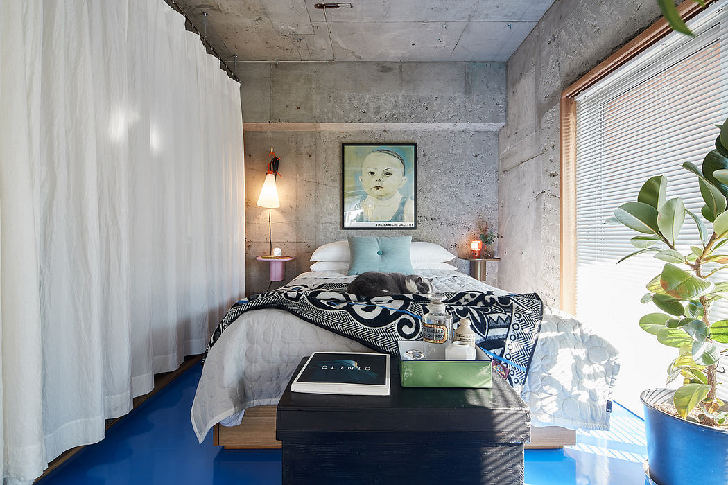 Cozy bedroom with concrete walls, wooden furniture, and modern artwork on display.
