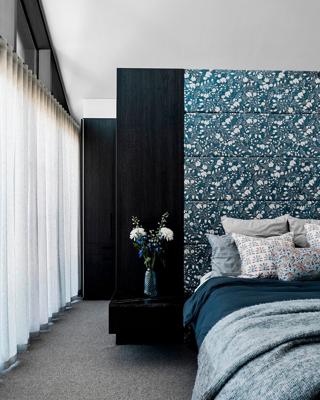 A modern bedroom with a patterned accent wall, minimalist furnishings, and soft textile accents.