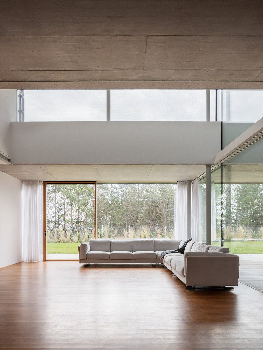 A modern living room with large windows, a sectional sofa, and a wooden ceiling.