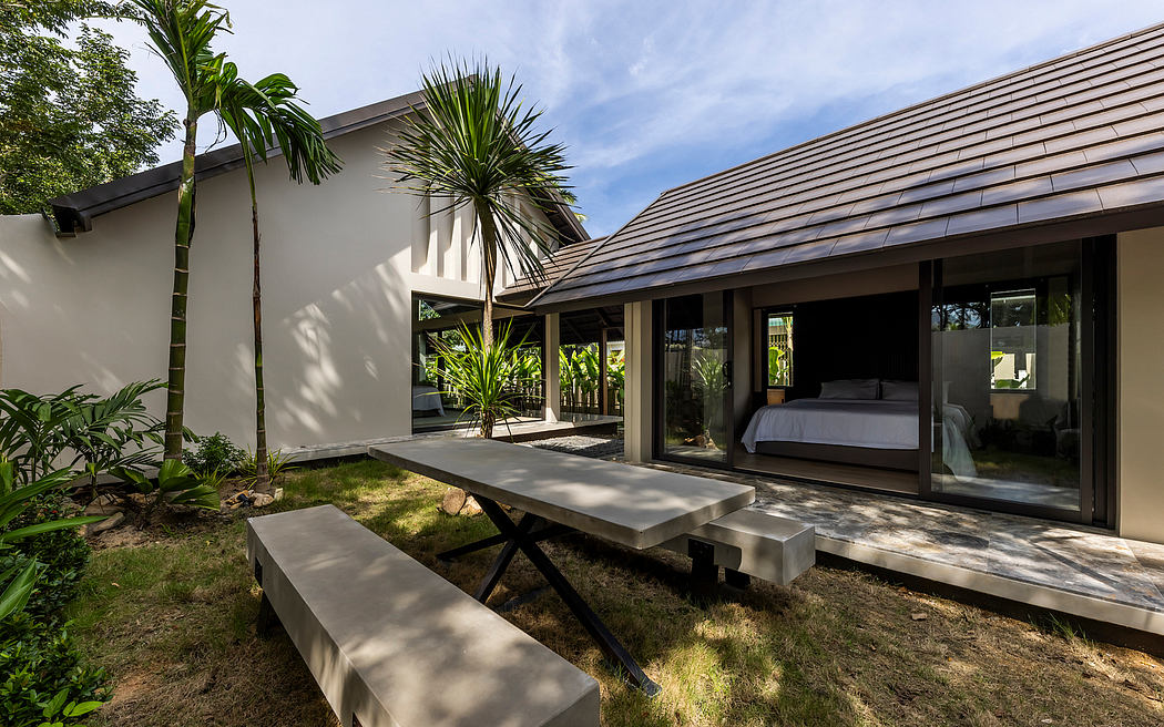 Modern tropical villa with sleek outdoor seating, lush greenery, and expansive glass walls.