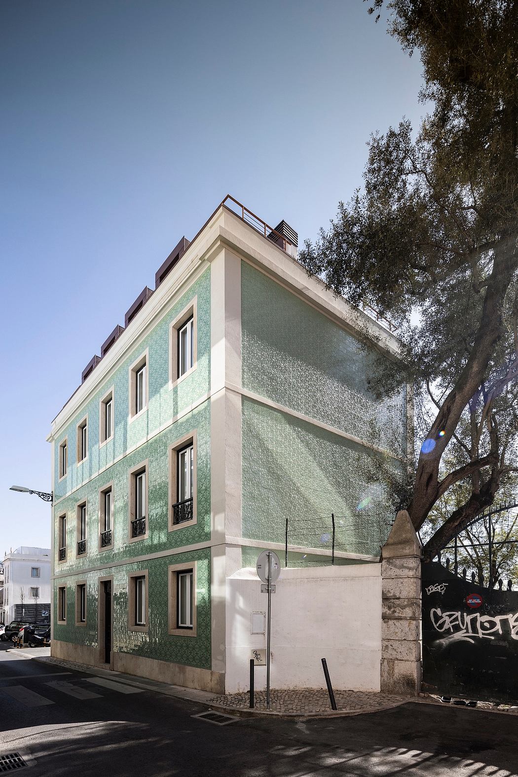 Ornate green-tile facade, clean lines, architectural details, tree-lined street.