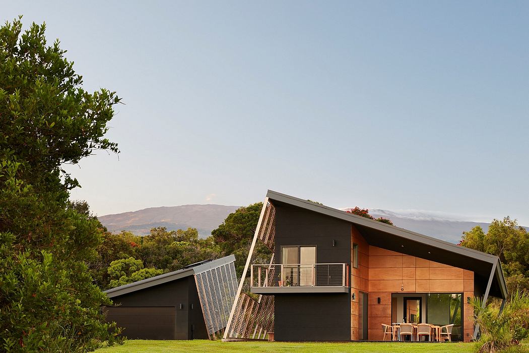 A modern, wood-paneled house nestled in a lush, green landscape with mountain views in the background.