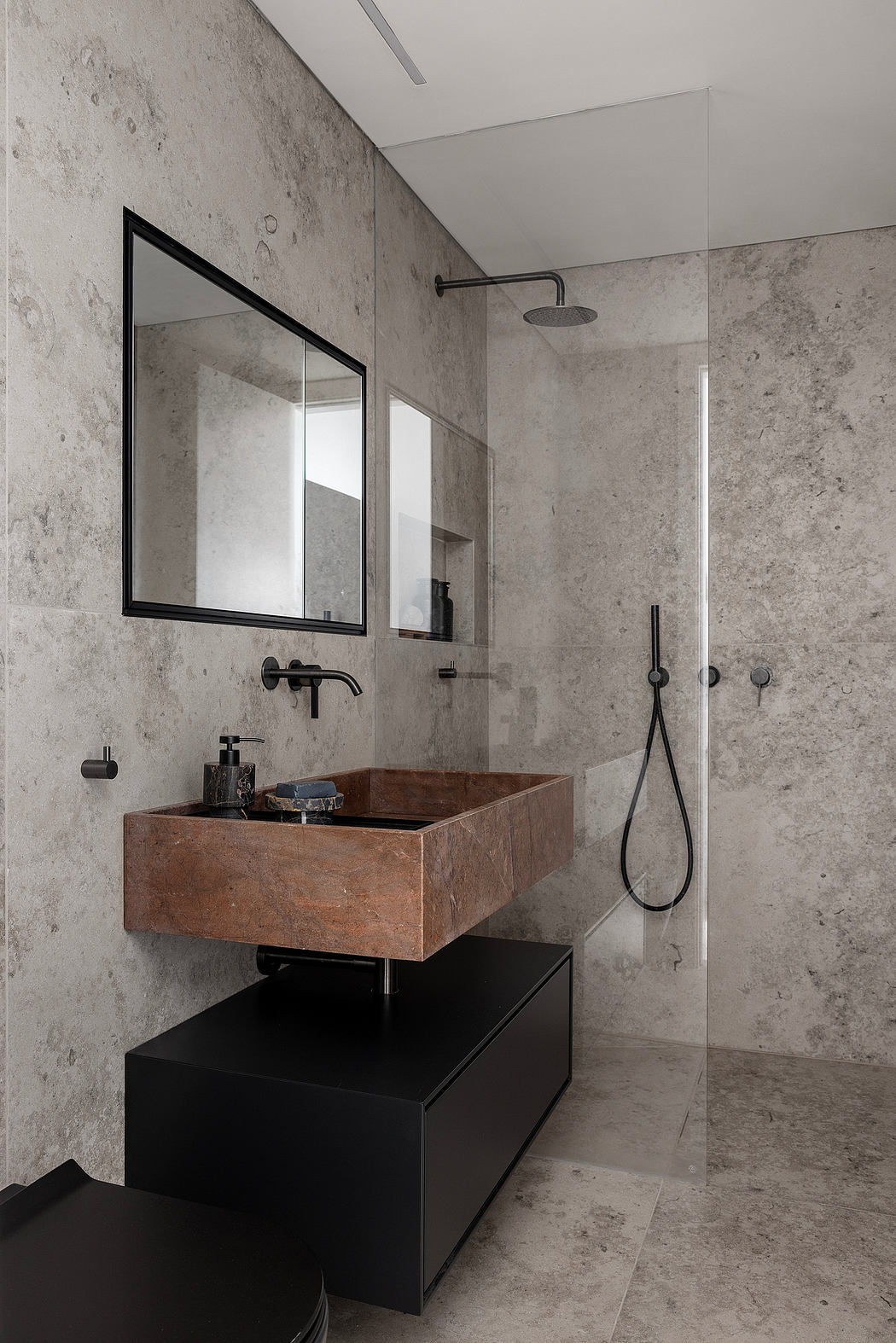 Minimalist bathroom with concrete walls, wooden vanity, and black fixtures.