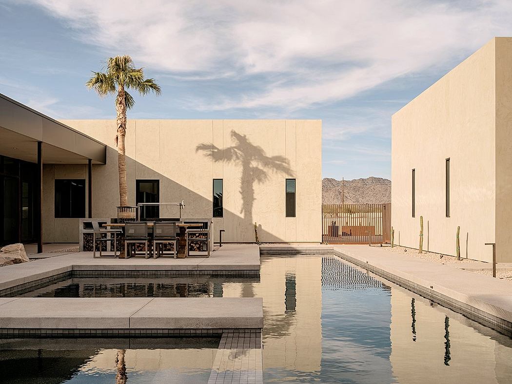 Minimalist desert-inspired architecture with a sleek pool, palm tree, and mountain backdrop.