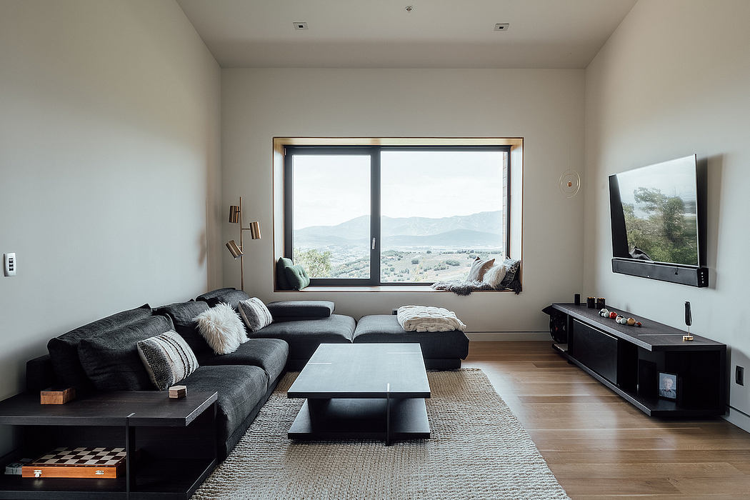 Spacious living room with large window offering scenic mountain view, modern furniture.