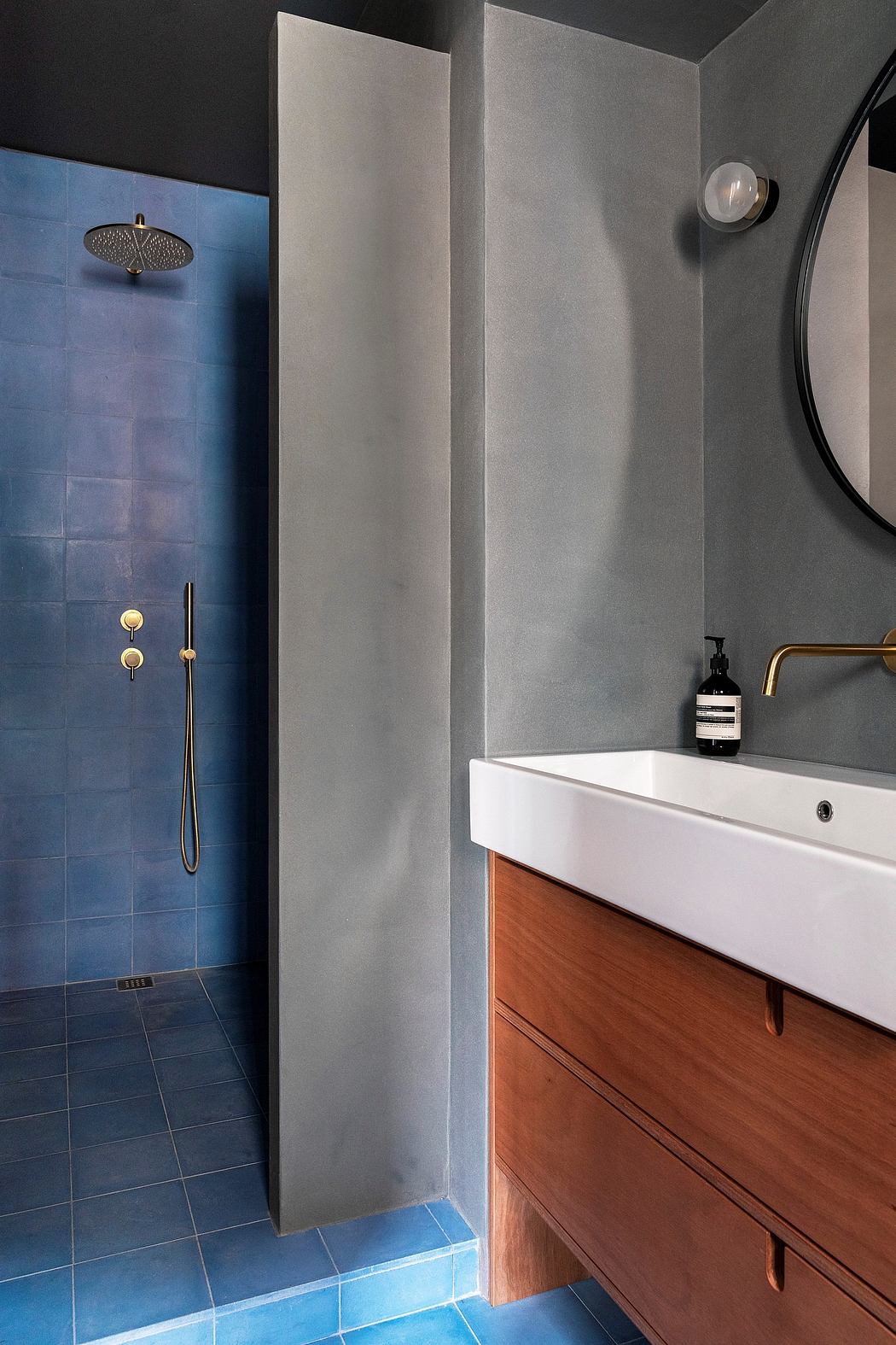 Minimalist bathroom design with blue tiled shower, wood vanity, and recessed lighting.