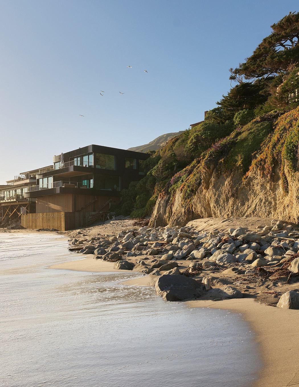 Modern beachfront apartments nestled among rugged cliffs, complementing the natural surroundings.