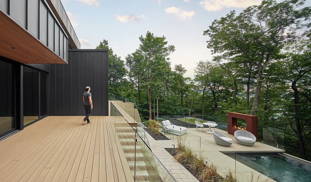 A modern, glass-and-wood house with a terrace, pool, and lush natural surroundings.