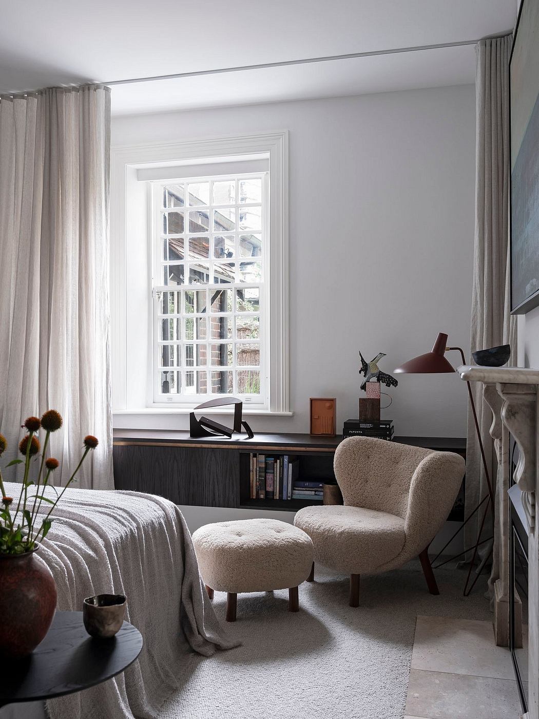 Cozy, neutral-toned bedroom with large window, plush chair, and earthy decor elements.