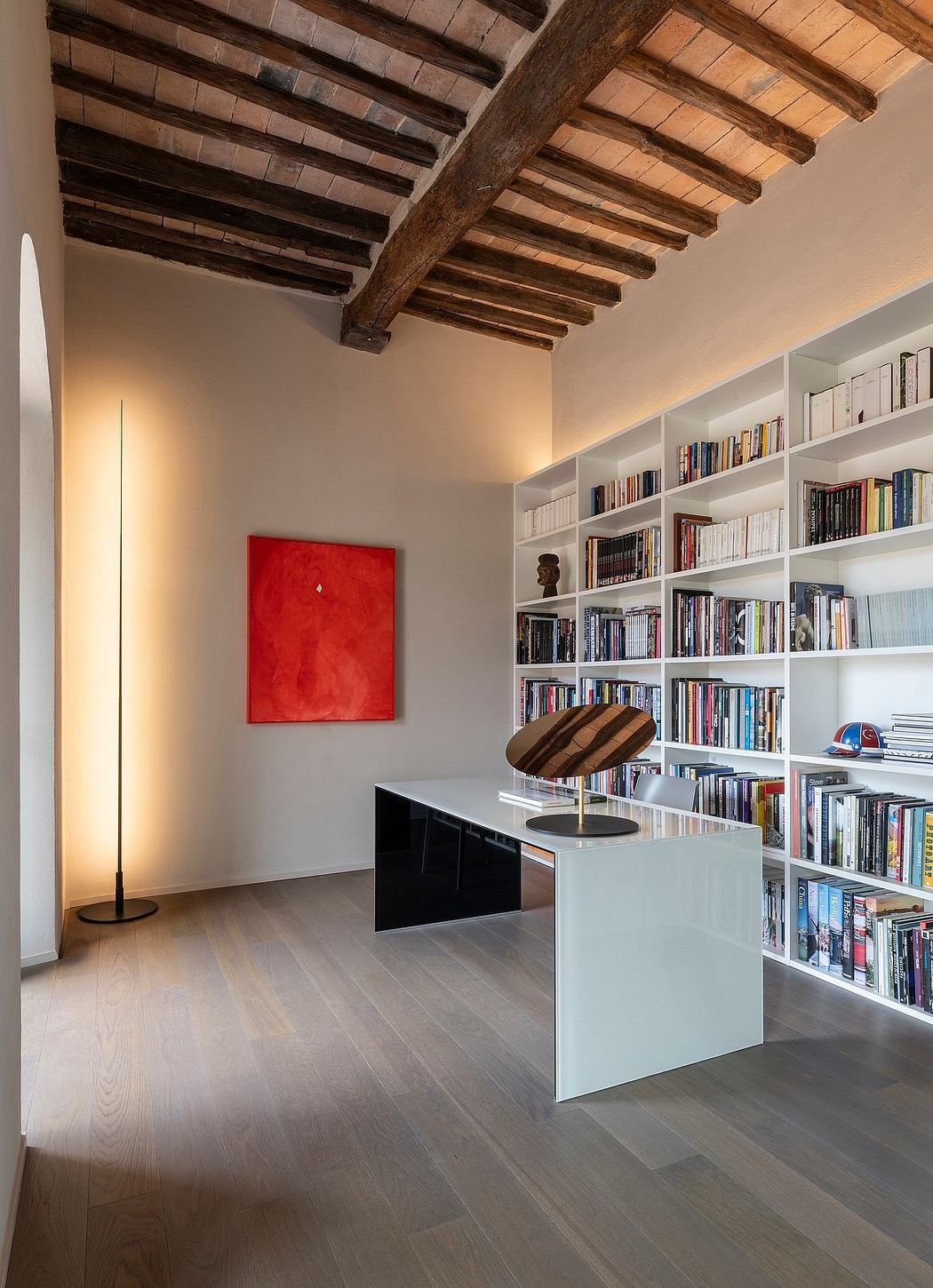 Wooden beamed ceiling, built-in bookshelves, modern furniture, and abstract red artwork.