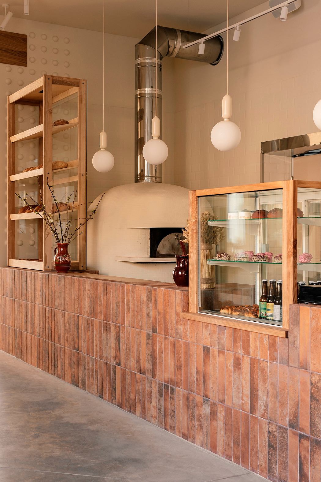Warm, rustic kitchen design featuring a brick-like tile backsplash, wood shelving, and a pizza oven.