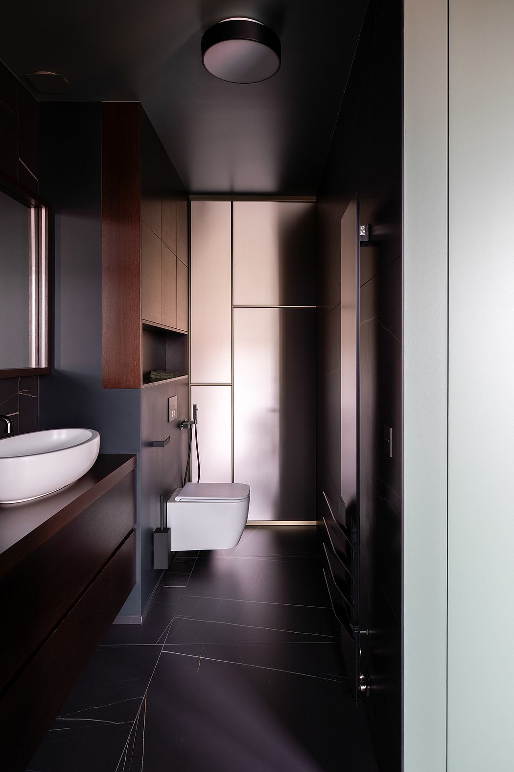 Sleek, modern bathroom design with minimalist cabinetry, dark tiled floor, and recessed lighting.