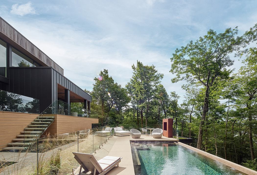 Sleek, modern house with glass walls, wooden accents, and an infinity pool surrounded by trees.