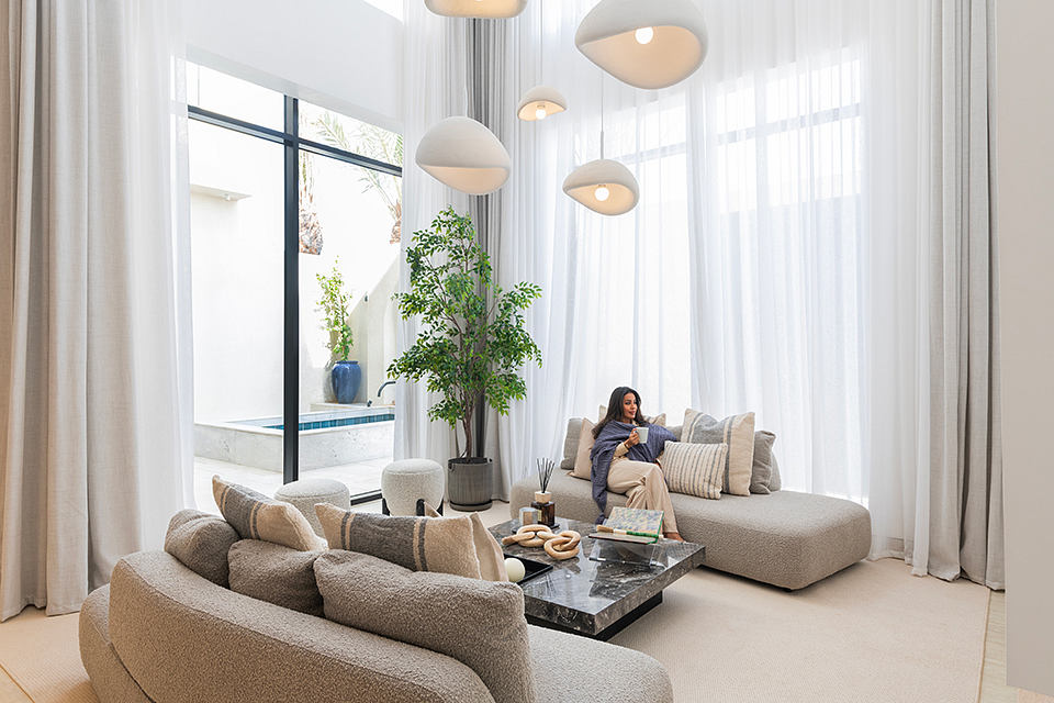 Elegant living room with modern furniture, pendant lights, and a potted plant.
