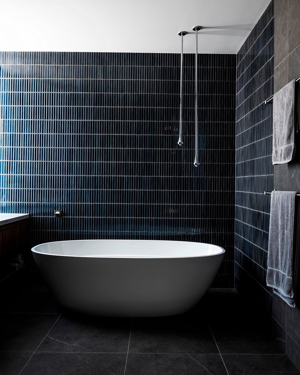 Sleek, minimalist bathroom with a freestanding bathtub, dark tiles, and modern shower fixtures.