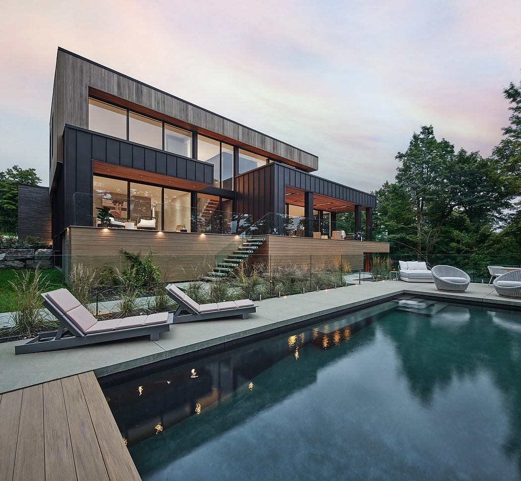 A modern, sleek house with a pool surrounded by lush greenery and a wooden deck.