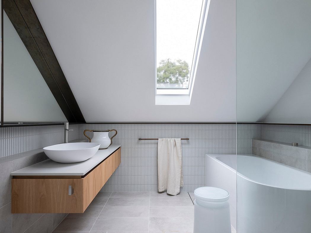 Modern, minimalist bathroom with wood vanity, white sink, and glass skylight.