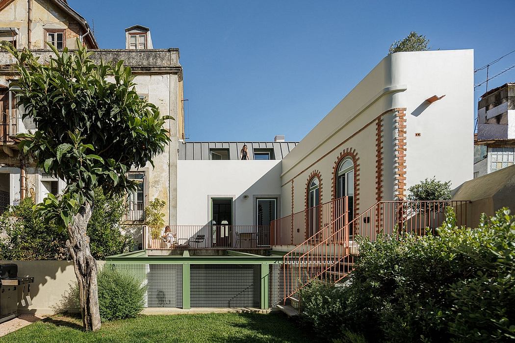 A modern white building with arched windows and a well-maintained garden in front.